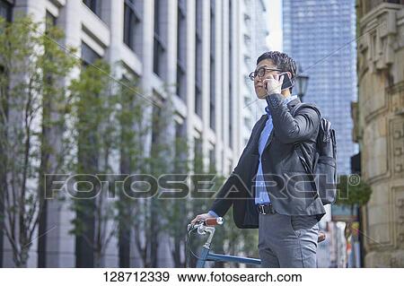 Middle Aged Japanese Businessman Riding A Bicycle View Large Photo Image Stock Photo - Middle Aged Japanese Businessman Riding A Bicycle. Fotosearch