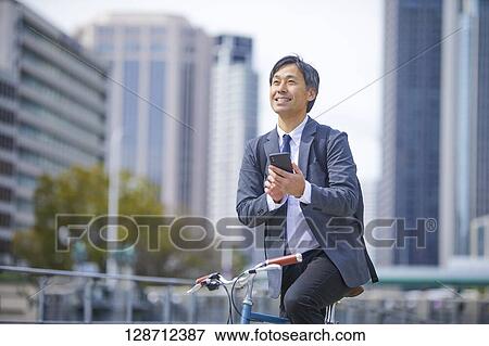 Stock Photo - Middle Aged Japanese Businessman Riding A Bicycle. Fotosearch
