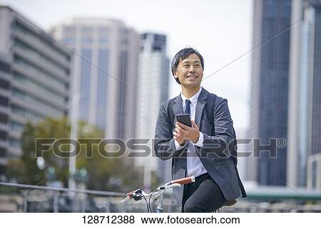 Stock Photo - Middle Aged Japanese Businessman Riding A Bicycle. Fotosearch