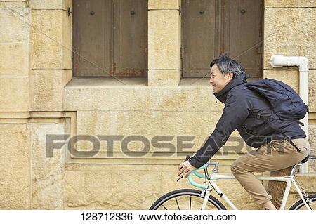 Stock Photograph - Middle Aged Japanese Businessman Riding A Bicycle. Fotosearch