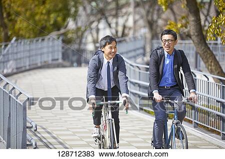 Stock Image - Middle Aged Japanese Businessmen Riding A Bicycle. Fotosearch
