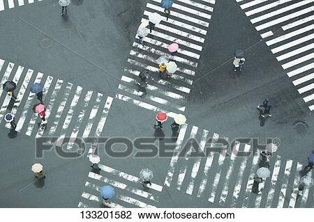 Stock Image - People Crossing A Crossroad On A Rainy Day In Tokyo, Japan. Fotosearch