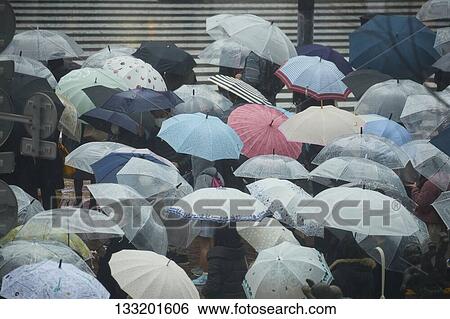 Stock Photograph - People Crossing A Crossroad On A Rainy Day In Tokyo, Japan. Fotosearch