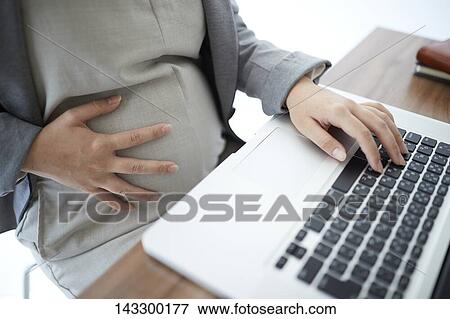 Stock Photo - Pregnant Japanese woman working with laptop. Fotosearch