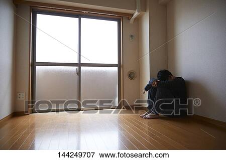 Stock Photo - Sad Japanese man in empty apartment. Fotosearch