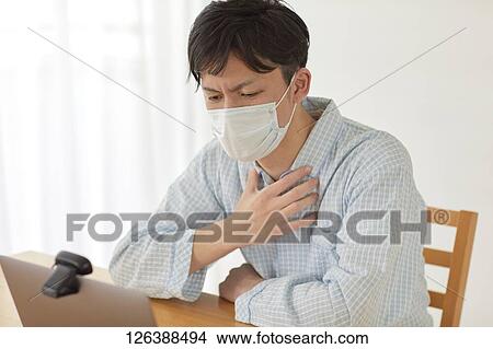 Picture - Sick Japanese man working from home. Fotosearch