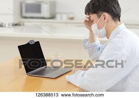 Stock Image - Sick Japanese man working from home. Fotosearch