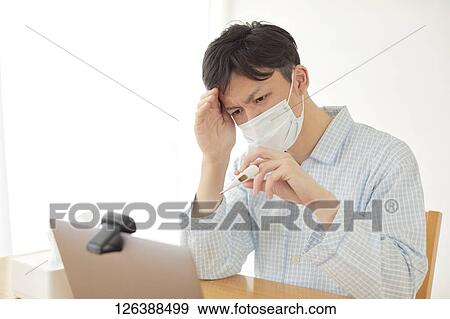 Stock Photo - Sick Japanese man working from home. Fotosearch