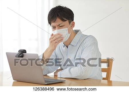 Stock Photograph - Sick Japanese man working from home. Fotosearch