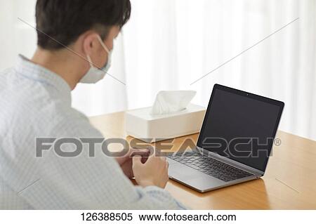Stock Photography - Sick Japanese man working from home. Fotosearch