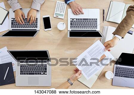 Stock Photo - Top-down view of business people working in the office. Fotosearch