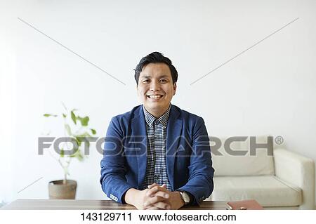 Stock Image - Young Japanese man having a remote video call. Fotosearch