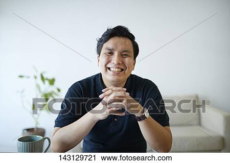 Stock Image - Young Japanese man having a remote video call. Fotosearch