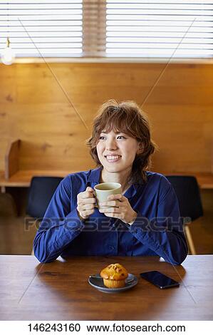 Stock Image - Young Japanese woman at a cafe. Fotosearch
