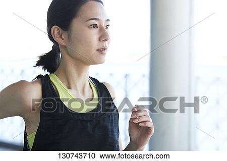 Stock Image - Young Japanese Woman Running Downtown Tokyo, Japan. Fotosearch
