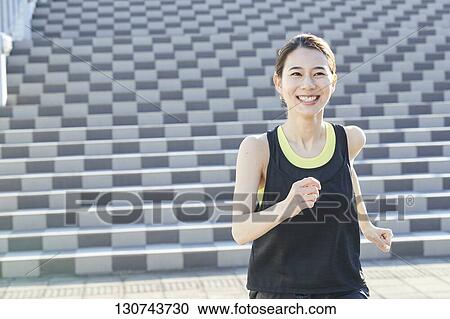 Stock Image - Young Japanese Woman Running Downtown Tokyo, Japan. Fotosearch