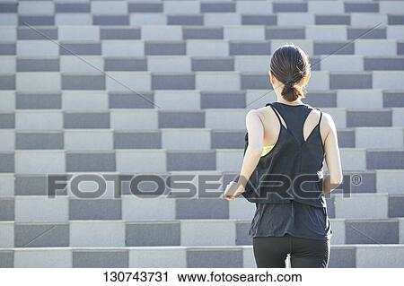 Stock Image - Young Japanese Woman Running Downtown Tokyo, Japan. Fotosearch