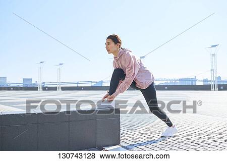 Stock Photo - Young Japanese Woman Stretching Downtown Tokyo, Japan. Fotosearch
