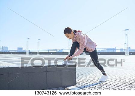 Stock Photograph - Young Japanese Woman Stretching Downtown Tokyo, Japan. Fotosearch