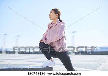 Stock Photograph - Young Japanese Woman Stretching Downtown Tokyo, Japan. Fotosearch