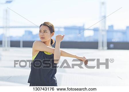 Stock Photograph - Young Japanese Woman Stretching Downtown Tokyo, Japan. Fotosearch