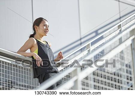 Stock Image - Young Japanese Woman Taking A Break During Jogging. Fotosearch