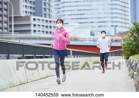 Stock Photo - Young Man And Woman Running With Face Mask. Fotosearch