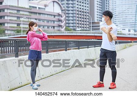 Picture - Young Man And Woman Stretching With A Face Mask. Fotosearch