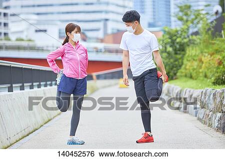 Stock Photograph - Young Man And Woman Stretching With A Face Mask. Fotosearch
