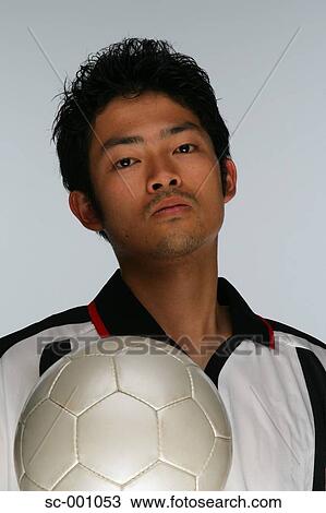 Stock Image - Confident soccer player holding ball. Fotosearch