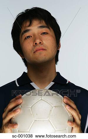Stock Photo - Confident soccer player holding ball to chest. Fotosearch