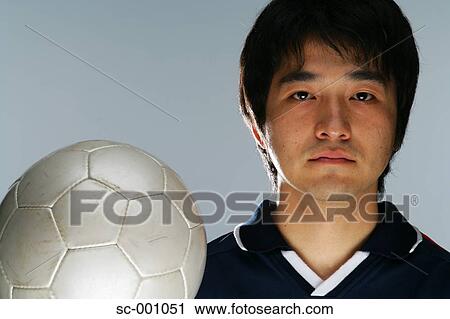 Stock Image - Determined soccer player holding ball. Fotosearch