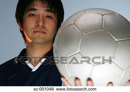 Stock Photo - Determined soccer player holding ball. Fotosearch