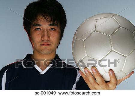 Stock Photo - Determined soccer player holding ball. Fotosearch