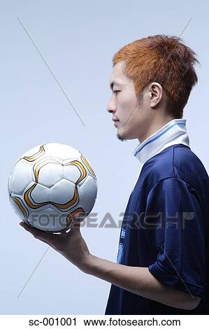 Stock Image - Side view of soccer player holding ball. Fotosearch