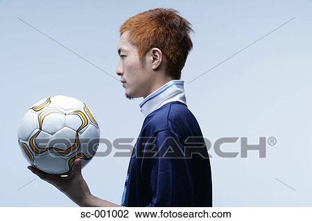 Stock Image - Side view of soccer player holding ball. Fotosearch
