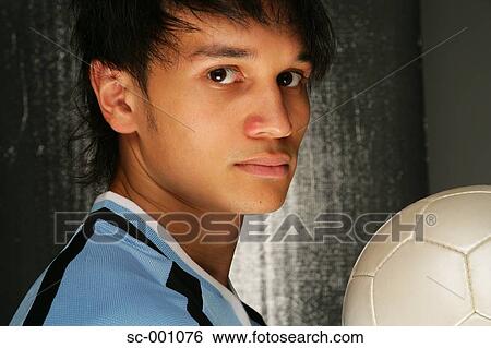 Stock Photograph - Side view of soccer player holding ball. Fotosearch