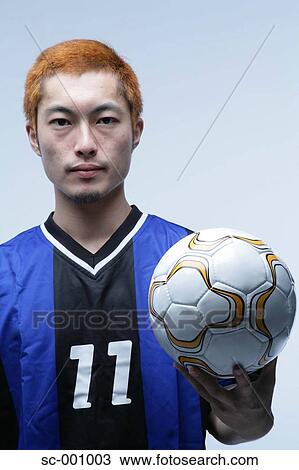 Stock Image - Soccer player holding ball. Fotosearch