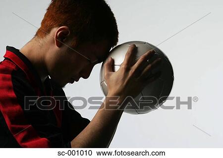 Stock Image - Soccer player holding ball to head. Fotosearch