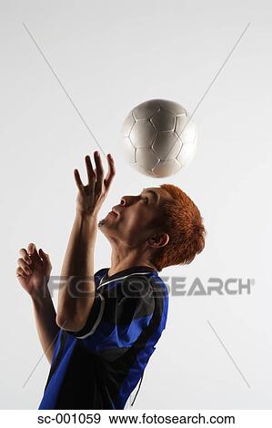 Stock Photo - Soccer player juggling ball on head. Fotosearch