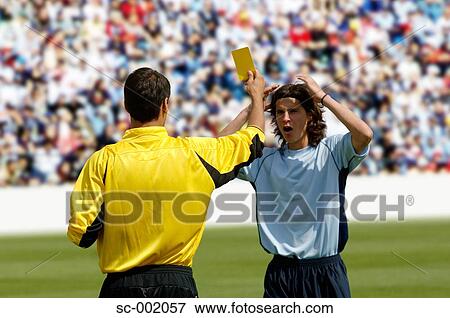 Stock Photo - Referee showing yellow card to disappointed player. Fotosearch