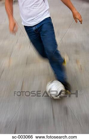 Stock Photograph - Man dribbling soccer ball in street. Fotosearch