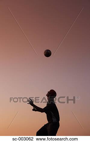 Stock Image - Silhouette of man juggling ball on head. Fotosearch