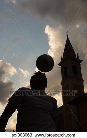 Stock Image - Silhouette of man juggling ball on head . Fotosearch