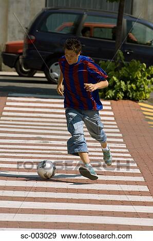 Teenage boy dribbling soccer ball in town View Large Photo Image Stock Photo - Teenage boy dribbling soccer ball in town. Fotosearch