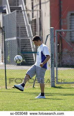 Stock Photo - Teenage boy juggling ball in park. Fotosearch