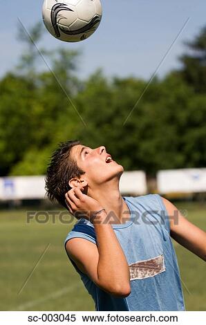 Stock Photography - Teenage boy juggling soccer ball with head. Fotosearch