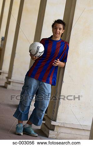 Teenage boy with ball leaning against pillar View Large Photo Image Stock Photograph - Teenage boy with ball leaning against pillar. Fotosearch