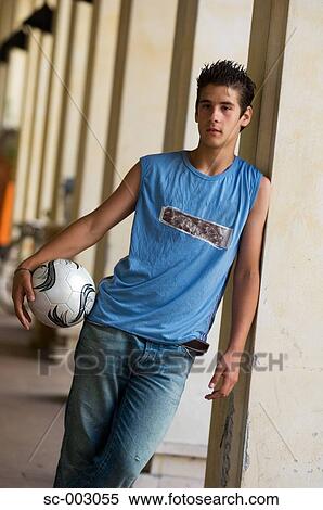 Stock Photography - Teenage boy with ball leaning against pillar. Fotosearch