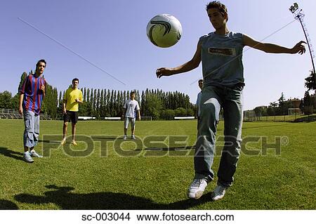 Teenage boys juggling ball in park View Large Photo Image Picture - Teenage boys juggling ball in park. Fotosearch